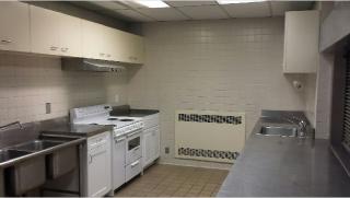 Our Kitchen: refrigerator, sinks, stove, microwave, large cutting table, serving window.